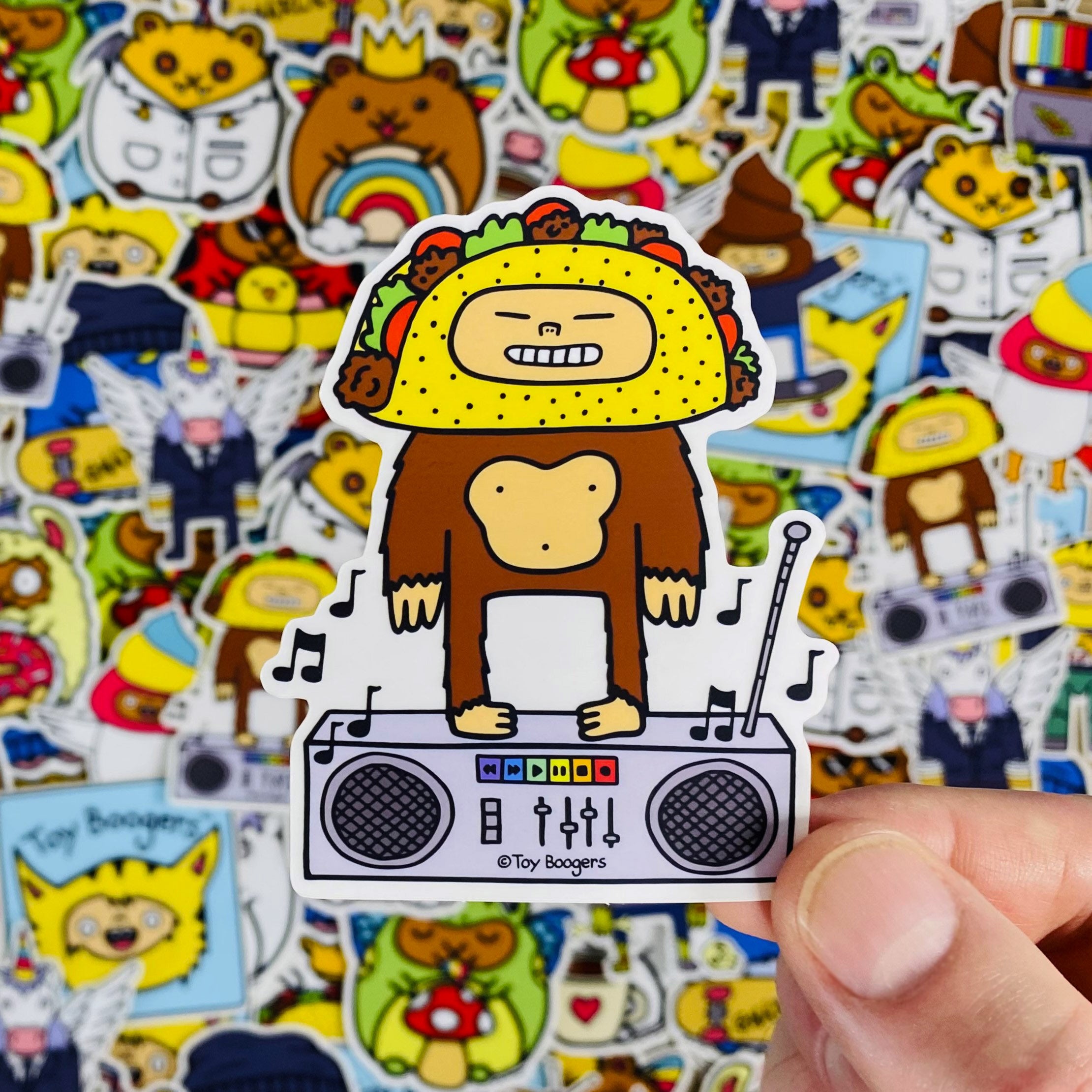 Funny sticker of a cartoon monkey with a taco head standing on a boombox.