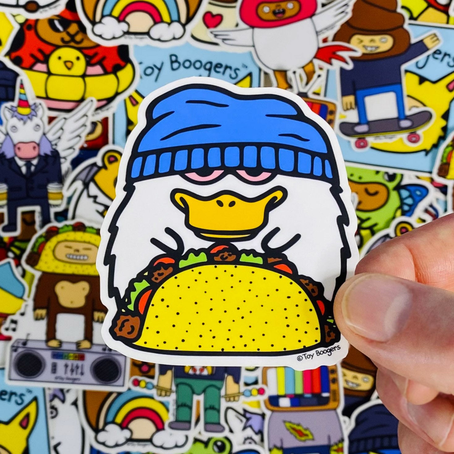 Funny sticker of a cartoon duck holding a taco and wearing a beanie.