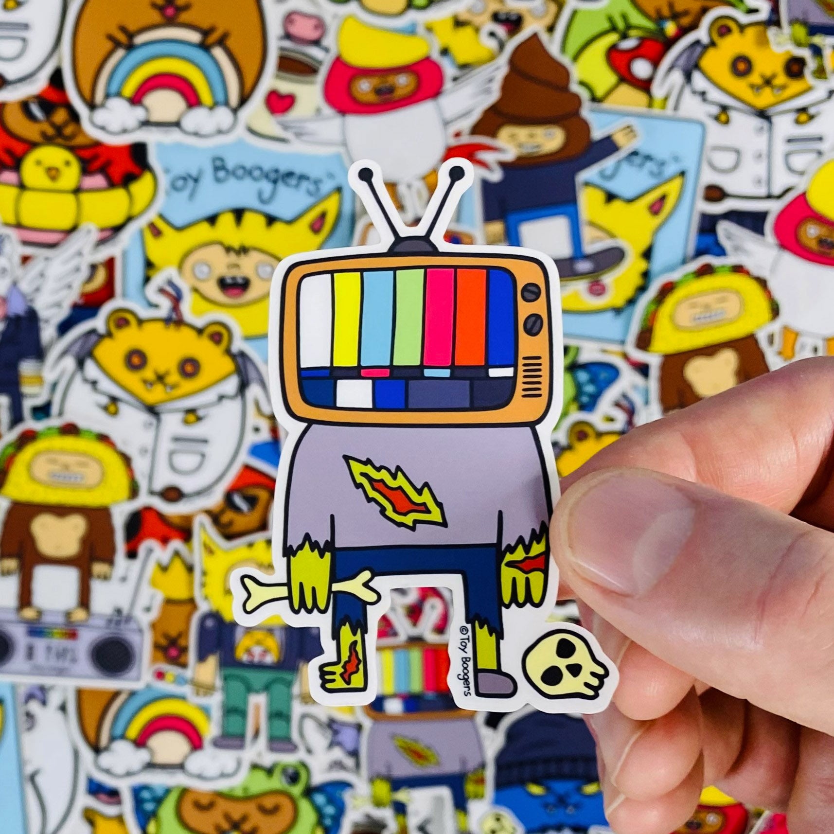 Funny sticker of zombie character with a TV head, holding bones and standing next to a skull.